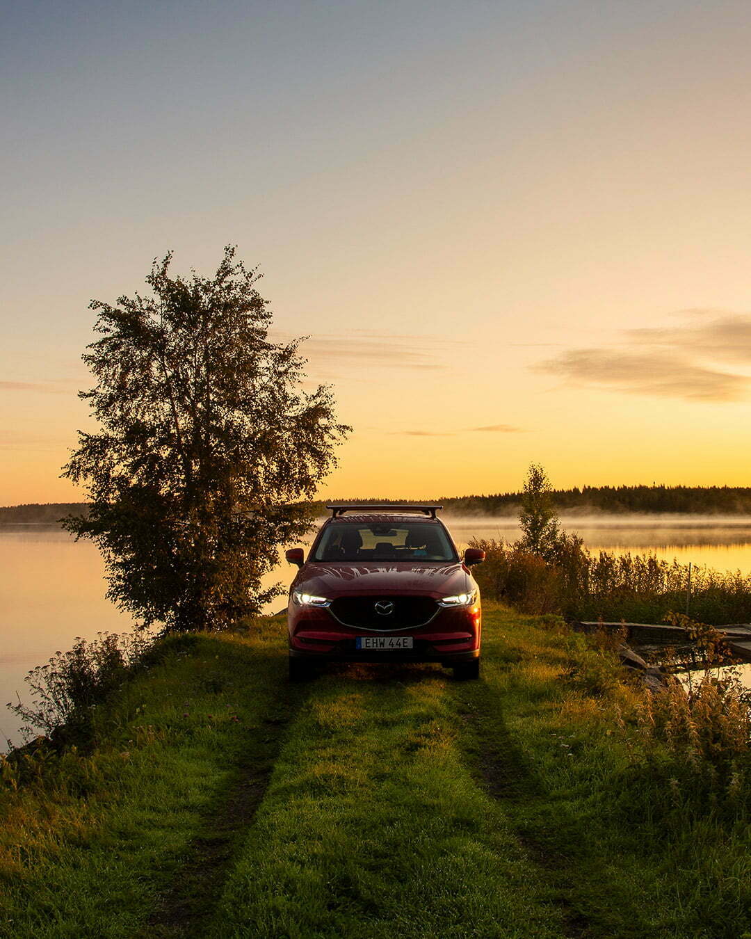 Mazda med kajak och gryning vid en sjö
